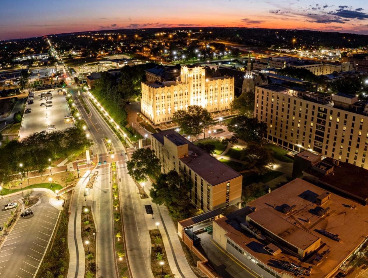 Horizon shot of Creighton campus with lights on as sun rises.