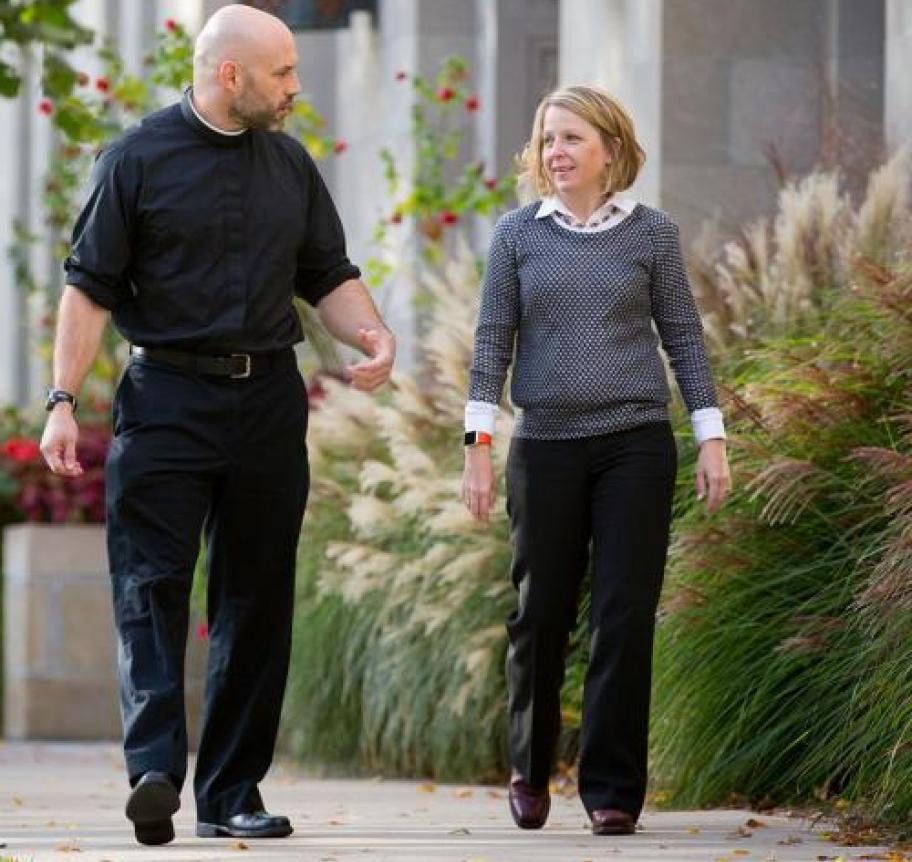 A priest and a woman speaking together while walking